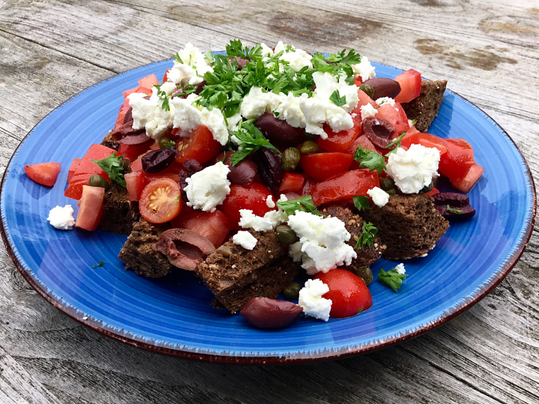 Dakos, Deze salade lijkt erg op Panzanella, de Toscaanse broodsalade.De toevoeging van olijven en fetakaas maken het echter typisch Grieks.Het speciale dakos, gedroogd krokant brood van Kreta, kennen wij hier niet dus hebben wij vervangen door gegrild volkorenbrood.Erg lekker als voorafje of lunchsalade.